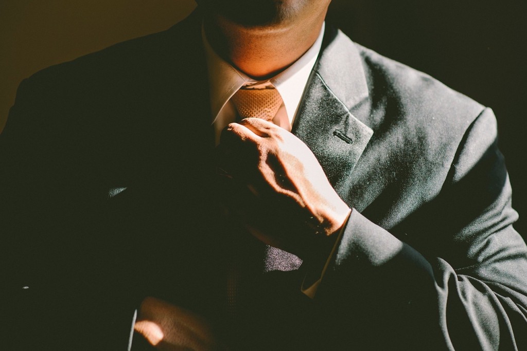 Hombre en traje acariciando (aka ajustando) corbata