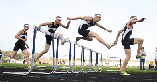 Row of people in a race jumping hurdles