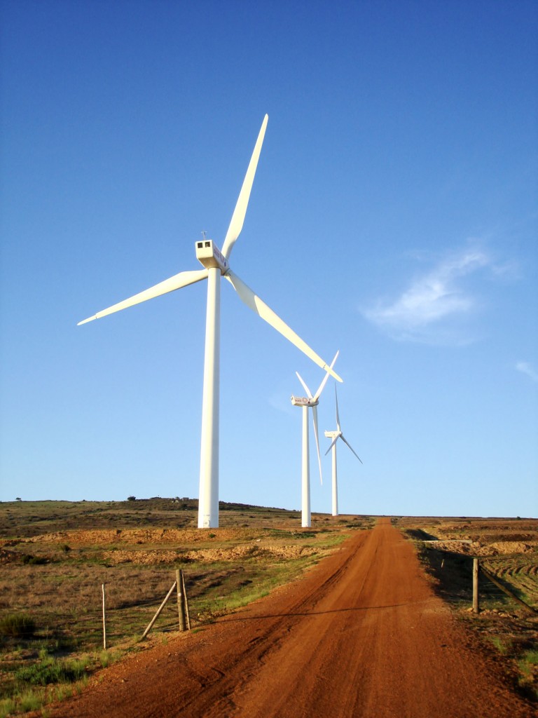 Tres turbinas de viento seguidas a lo largo de un camino de acceso de tierra
