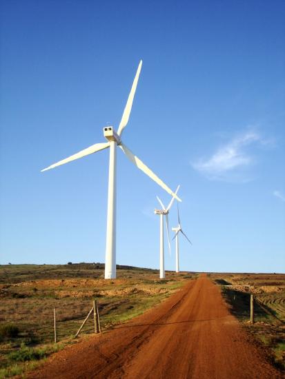 Three wind turbins in a row along a dirt access road