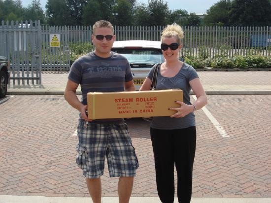 Smiling customers in a parking lot holding a box with a purchase