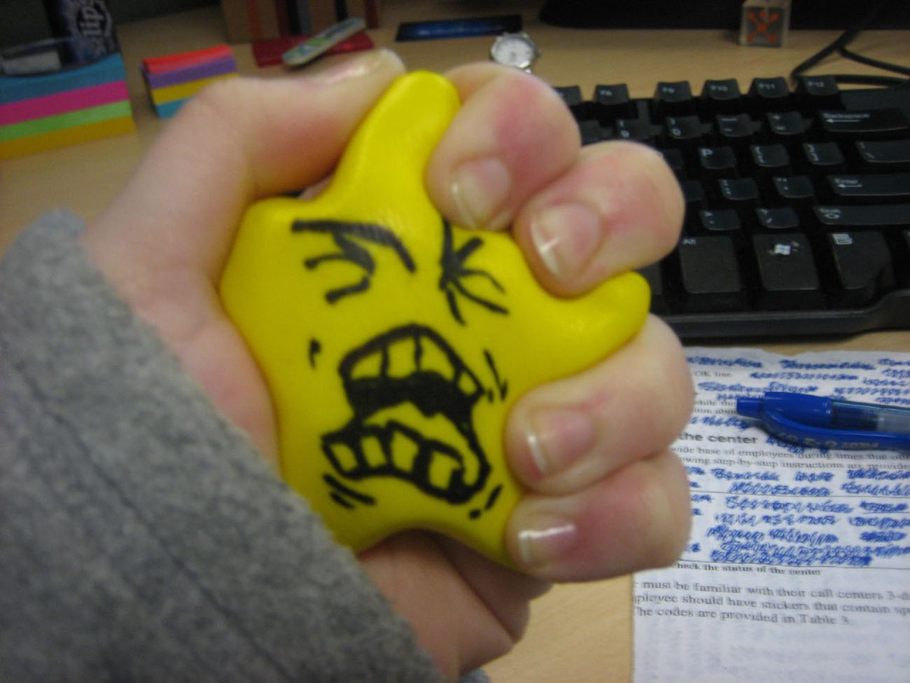 Una foto muestra una mano apretando una estrella de espuma impresa con una cara enojada y gritando.