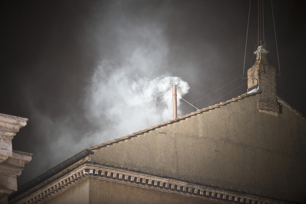 A photo shows white smoke rising from the chimney of the Sistine Chapel in Vatican City.
