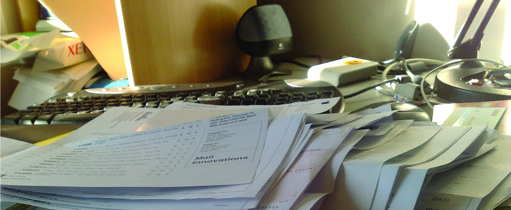 Photographie d'un bureau en désordre rempli de papiers, avec un clavier d'ordinateur en arrière-plan.