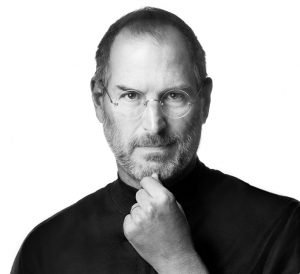 Black and white photo of Steve Jobs wearing characteristic black turtleneck and pinching his chin between forefinger and thumb