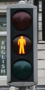 A photograph of a stoplight, with the silhouette of a person lit up in the center, yellow light.