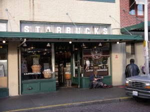 A photograph of the storefront of the first Starbucks store with iconic green awning viewed from a street.