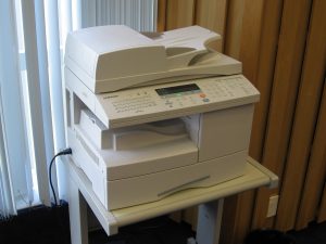 A photograph of a printer sitting on a table just slightly larger than the base of the printer.