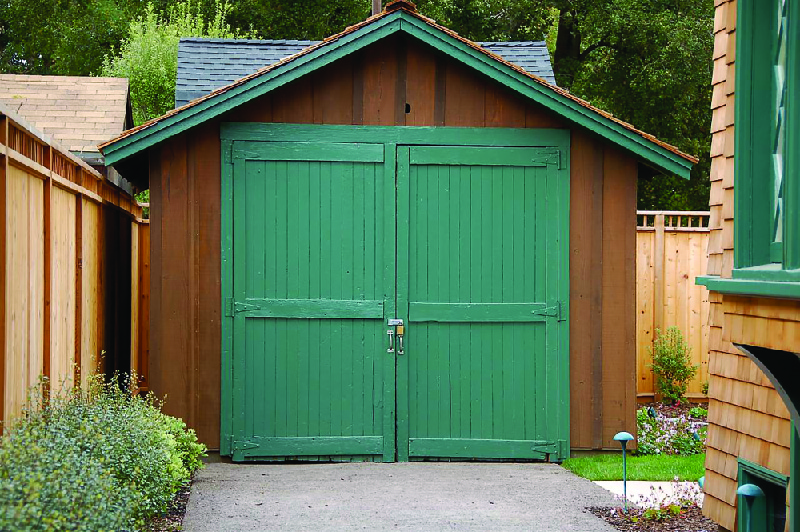 Esta imagem mostra uma pequena garagem de madeira em um quintal.