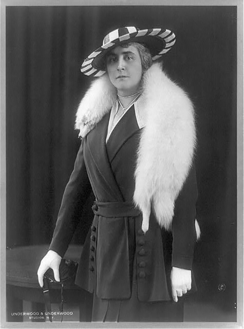 Esta imagem mostra Anne Morgan usando uma estola de raposa sobre os ombros, luvas, um chapéu e uma jaqueta e saia.