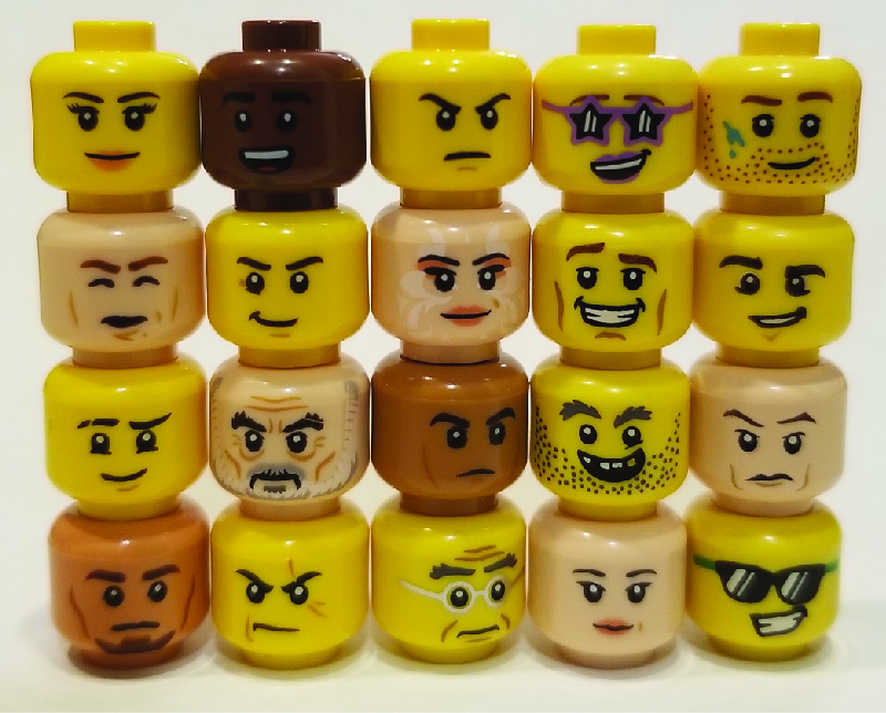 L'image montre des têtes de figurines Lego empilées sur cinq colonnes, avec quatre têtes dans chaque colonne. Les têtes présentent une variété d'expressions.
