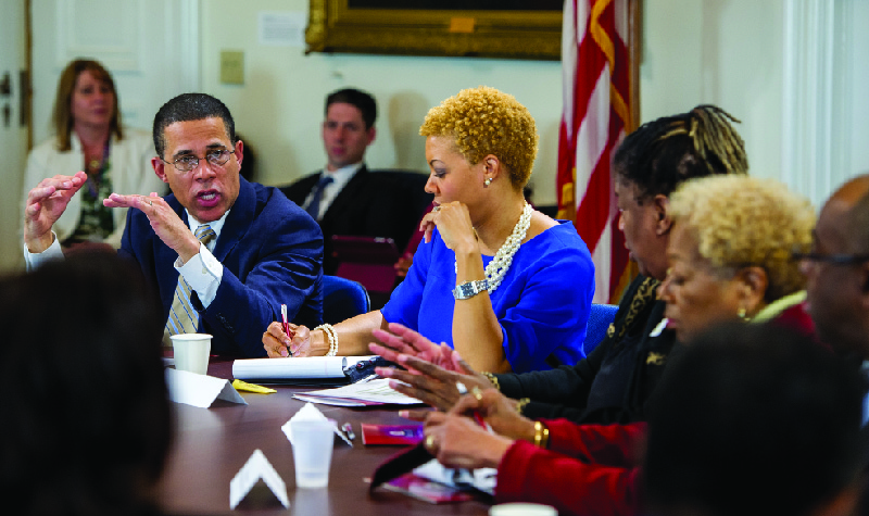 Esta imagem mostra um grupo de homens e mulheres sentados ao redor de uma mesa em discussão.