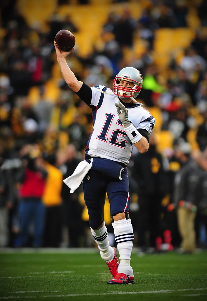 Uma fotografia de Tom Brady em um campo jogando um passe.