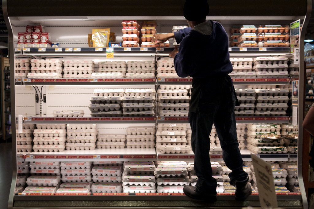 Uma equipe empilha ovos nas prateleiras de um supermercado.