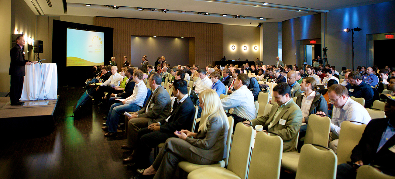 Uma foto mostra um homem em uma sala de conferências dirigindo-se aos participantes.