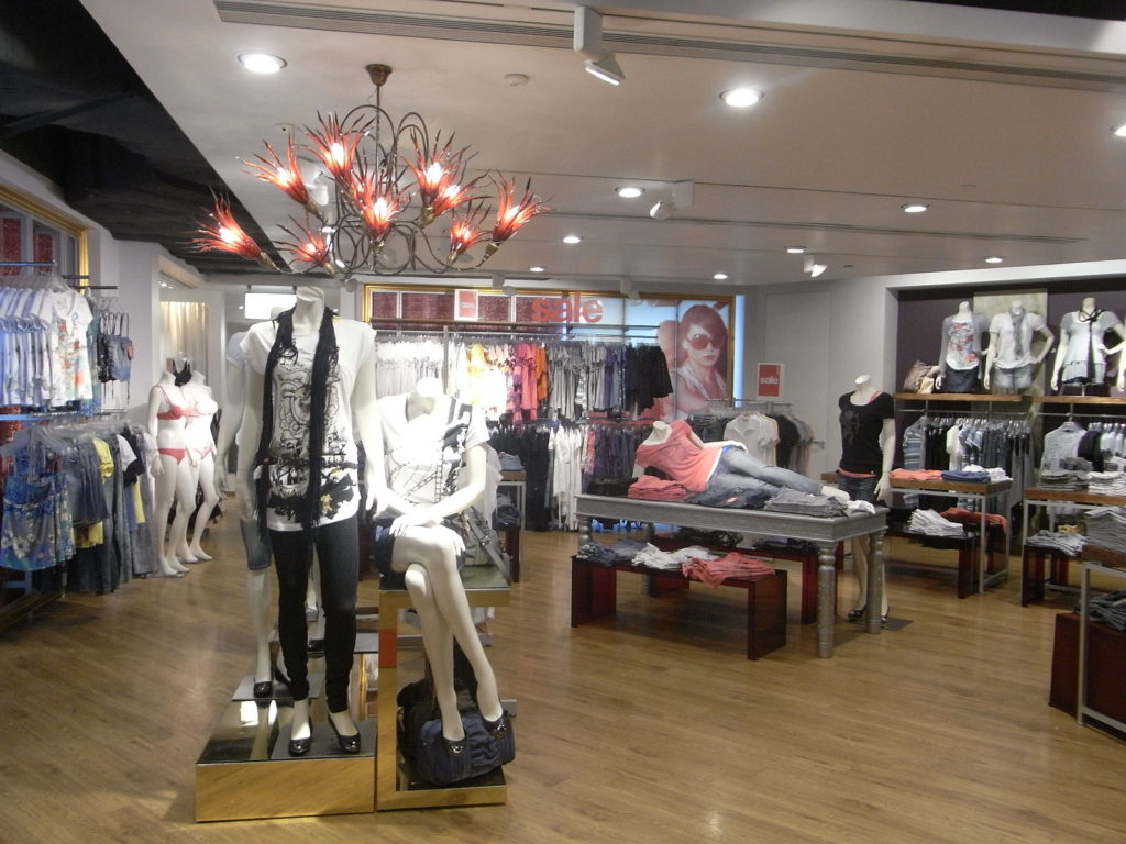 Photograph of a clothing store interior. The shelfs are placed at 90 and 45 degree angles from one another, creating a more trendy vibe.