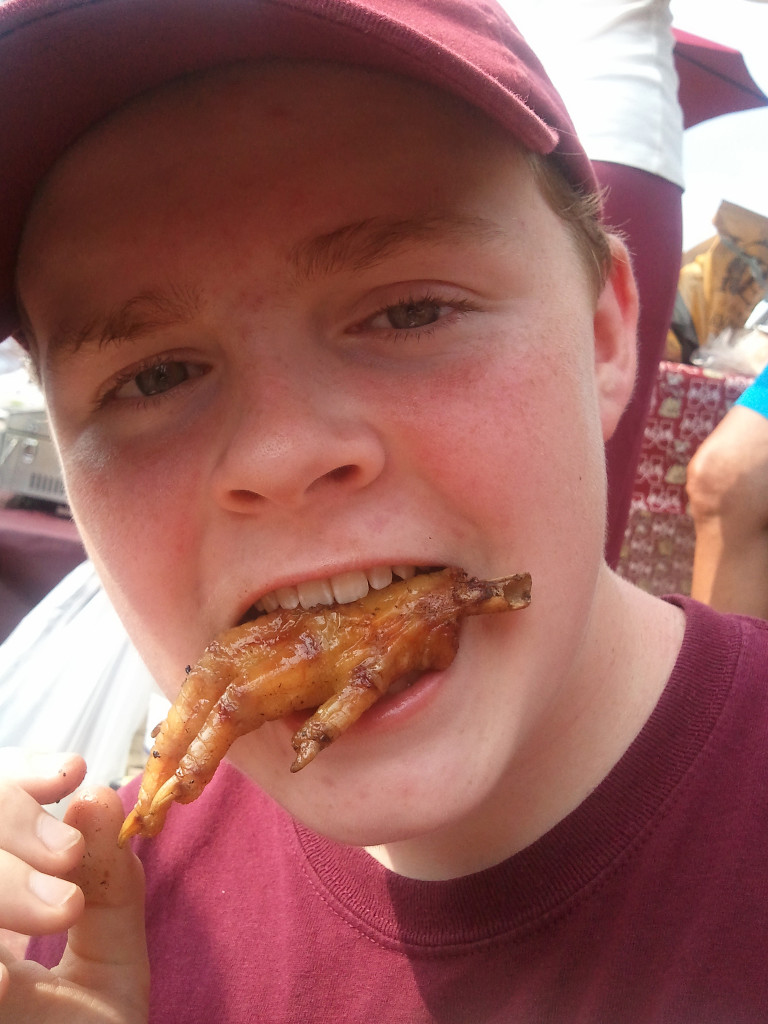 A boy eating a fried chicken foot