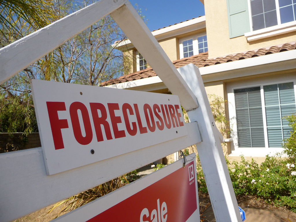 A house with a "foreclosure" sign in the foreground