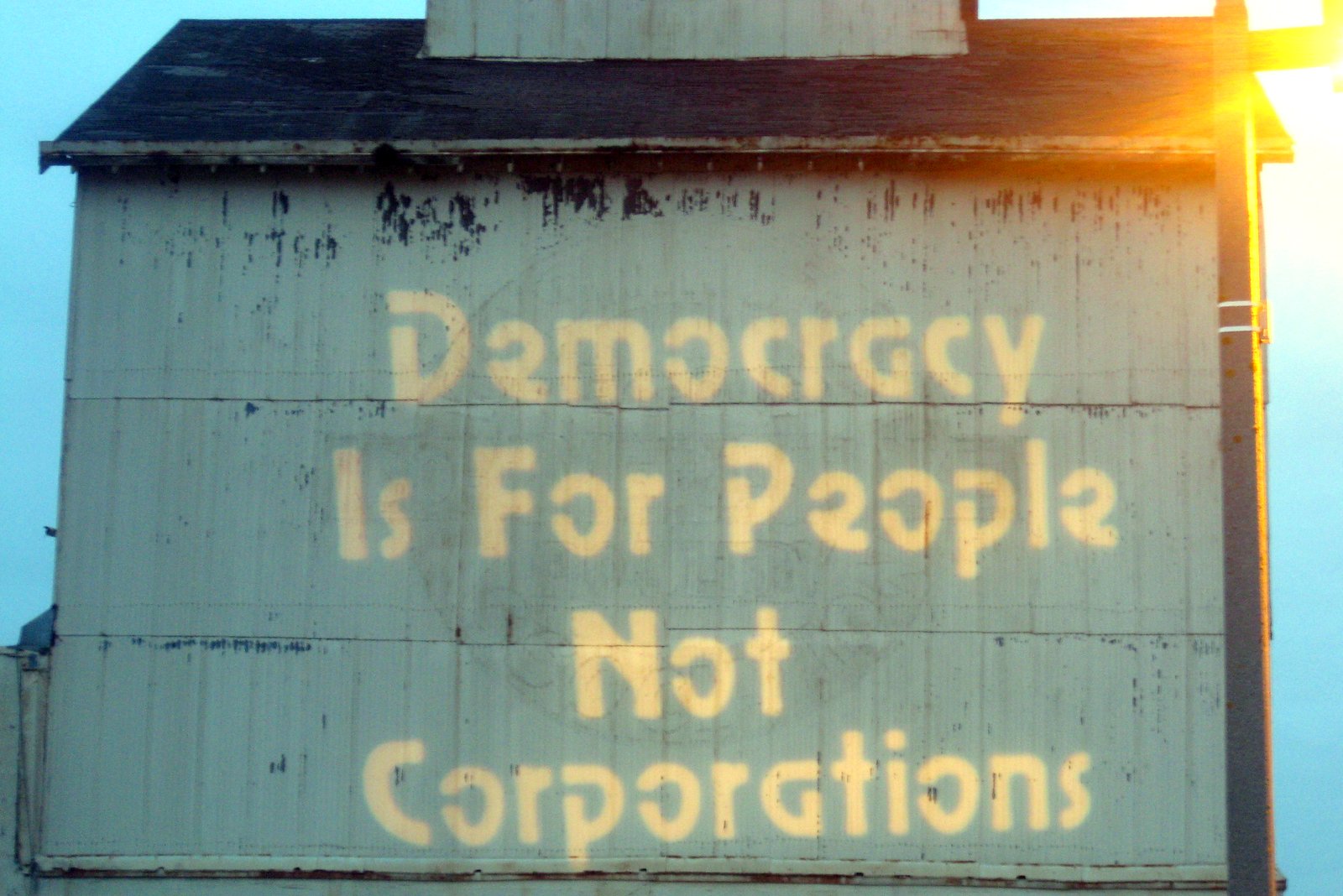 An old building with the words "Democracy Is For People, Not Corporations" painted on it