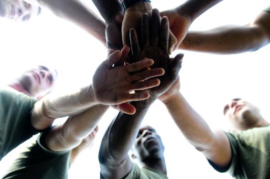 team huddle where each person places a hand in the center atop another member's hand.