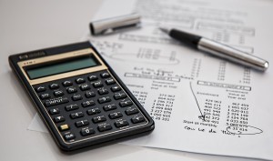 calculator, pen, and a budget sheet on a desk