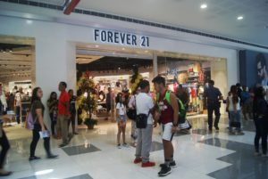 An image of the mall entrance to a Forever 21 store with lots of people walking around in front of the store.