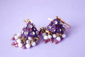 Image of two gold earrings made of tiny white, purple, and pink beads.