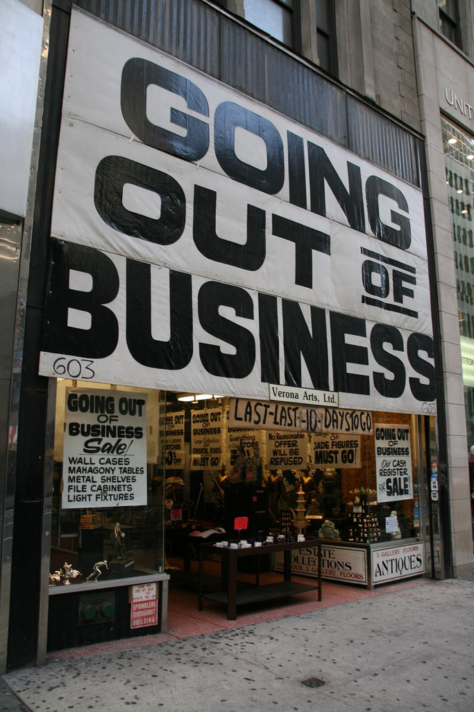 A store front with a large sign in black and white that says "going out of business".