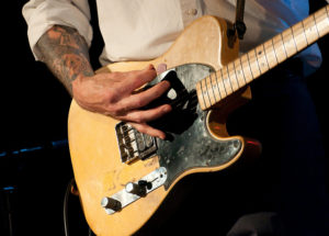 Man strumming an electric guitar during a rock concert.