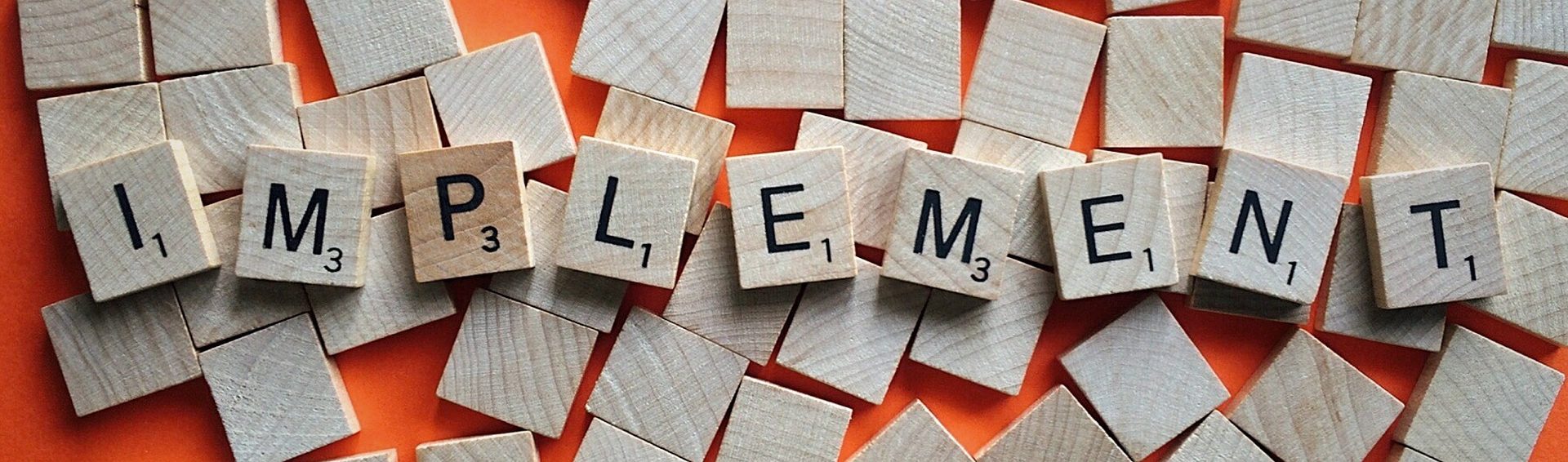 A photograph of scrabble tiles spelling out the word "implement"