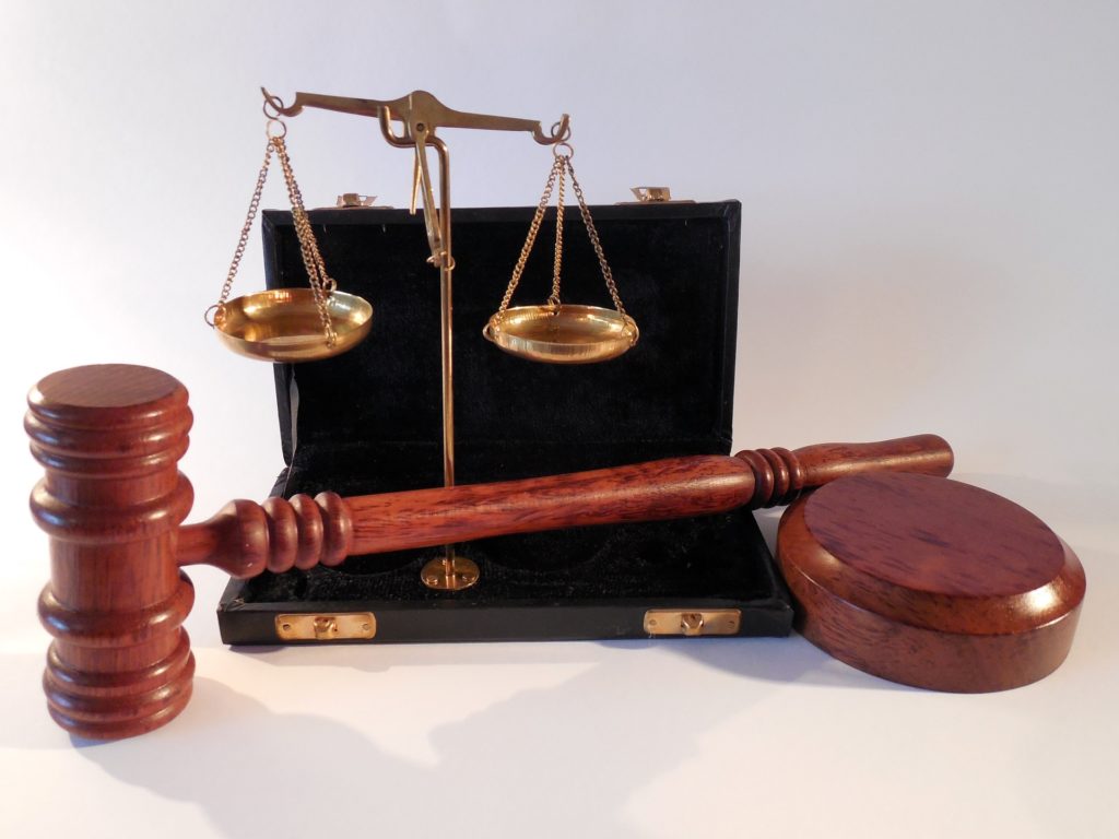 Photograph of a wooden gavel and small metal scales.