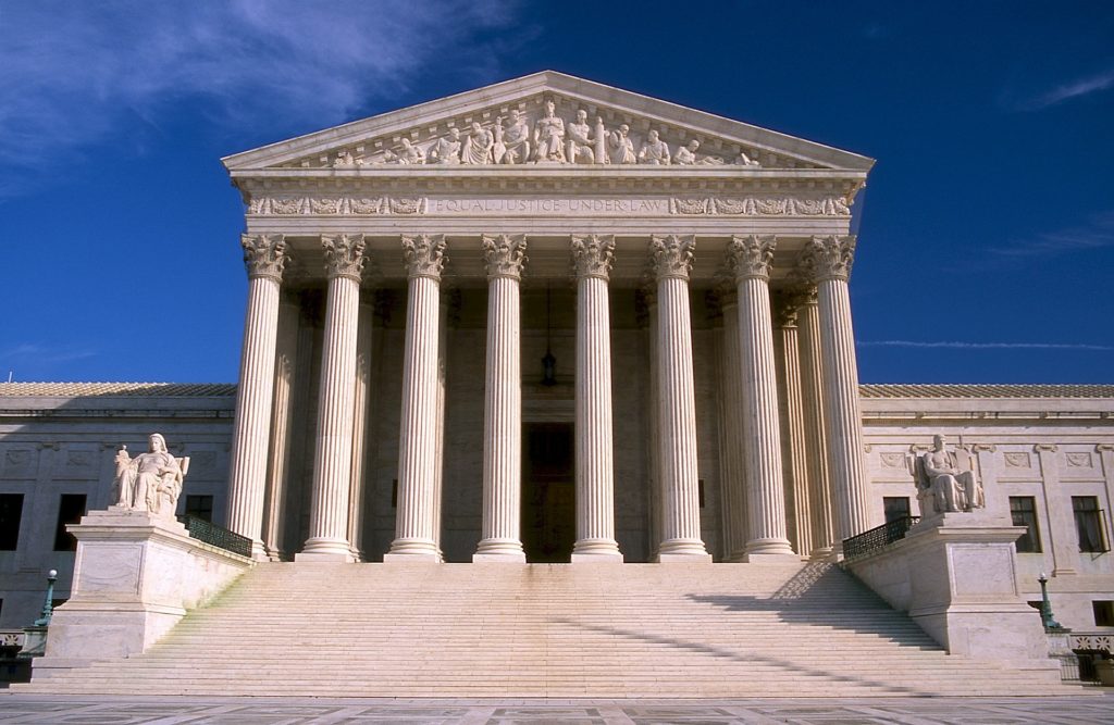 Photo of the Supreme Court Building. It has a Roman style, with large white columns and sculptures of people in the Tympanum. The Frieze has the words "Equal Justice Under Law" on it.