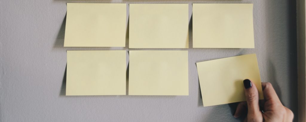 Photograph of six sticky notes on a wall.