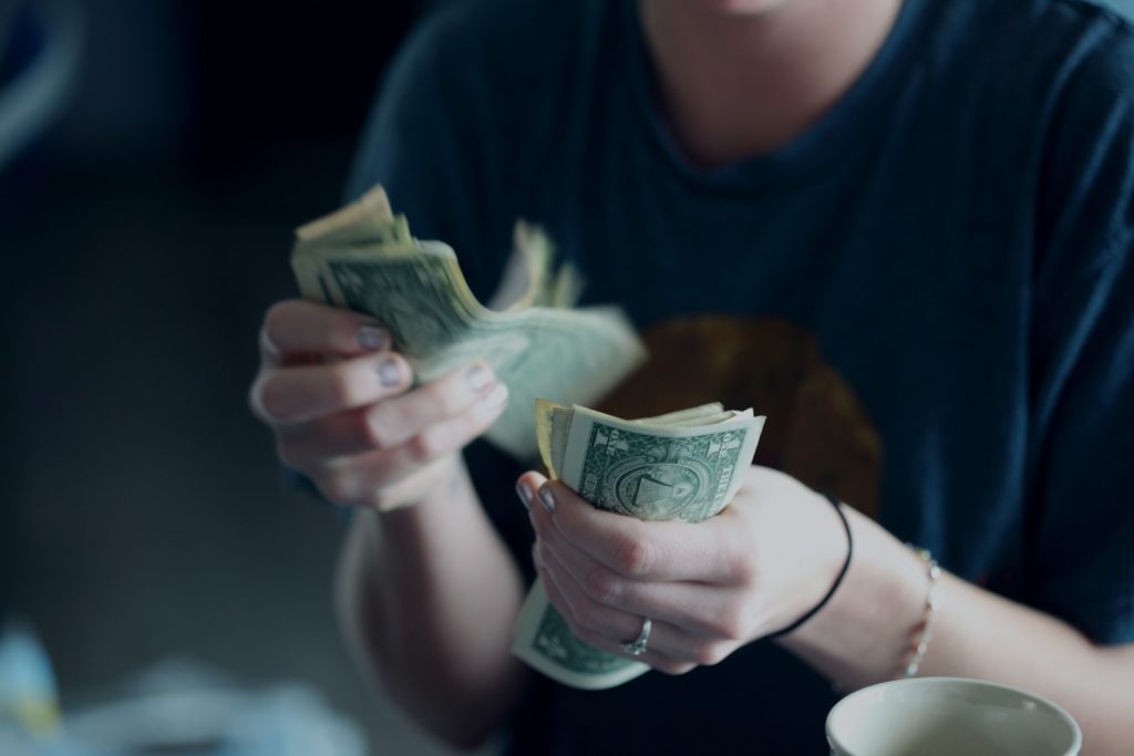 Photograph of a woman counting dollar bills.