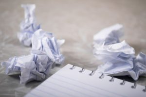 A blank notepad and paper crumpled into balls.