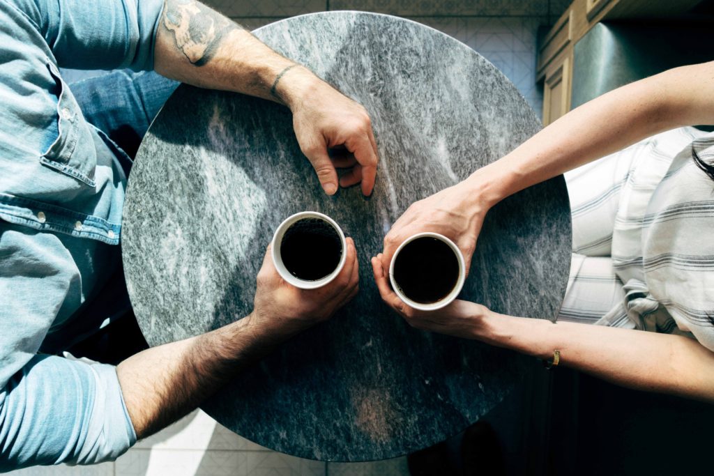 Photograph of two people sitting at a table with coffee cups.