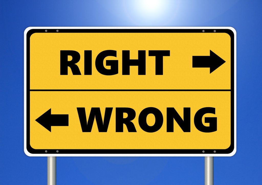 Photograph of a sign pointing one direction for right and the opposite direction for wrong.