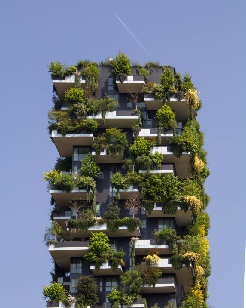 Photograph of a tall building. Every balcony has an overflowing garden; there is more greenery than building visible.