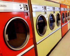 Photo of a row of orange and yellow coin-operated washing machines.