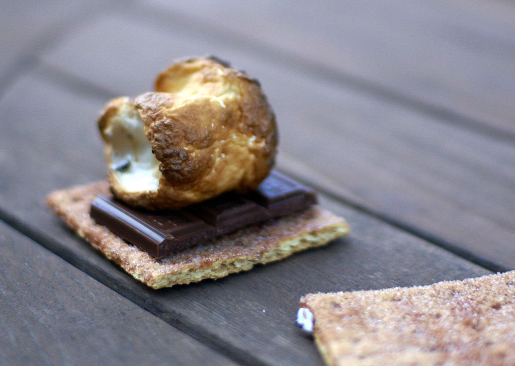 Photo of a s'more: perfectly toasted marshmallow atop a square of chocolate on a graham cracker.