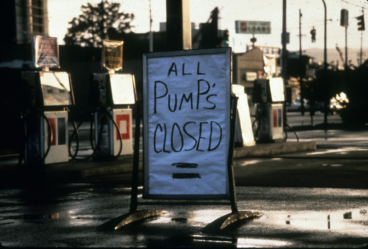 Hand written sign in front of gas station saying "All Pump's Closed"