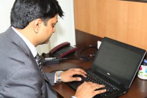 A businessman works at a desk on a laptop computer.