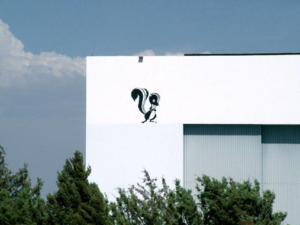 A white building with a cartoon skunk painted on the side, against a blue sky backdrop