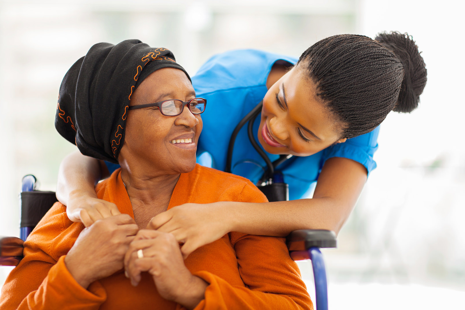 Friendly nurse talking with elderly patient in wheelchair
