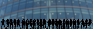 Silhouettes of many business people in front of a large building in the background.