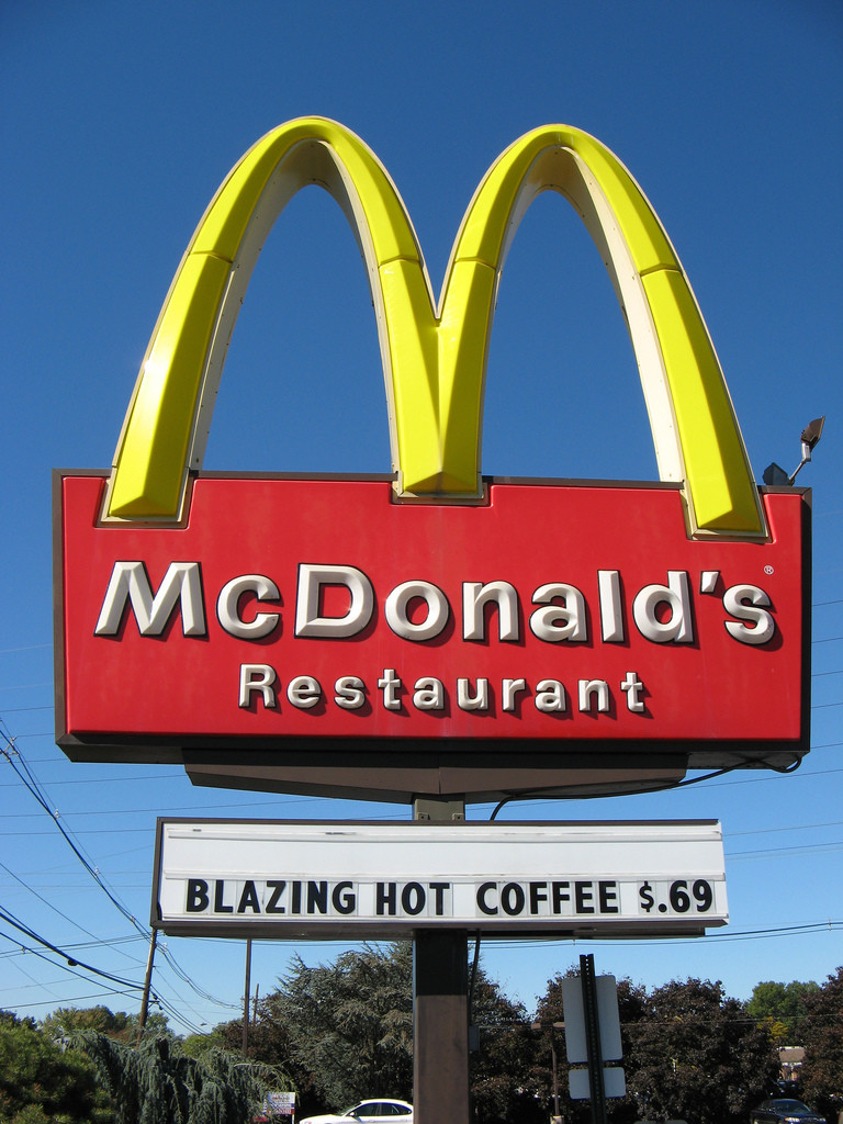 Photo of McDonald's Restaurant sign (with the famous golden arches) that reads underneath, "Blazing hot coffee, 69 cents."