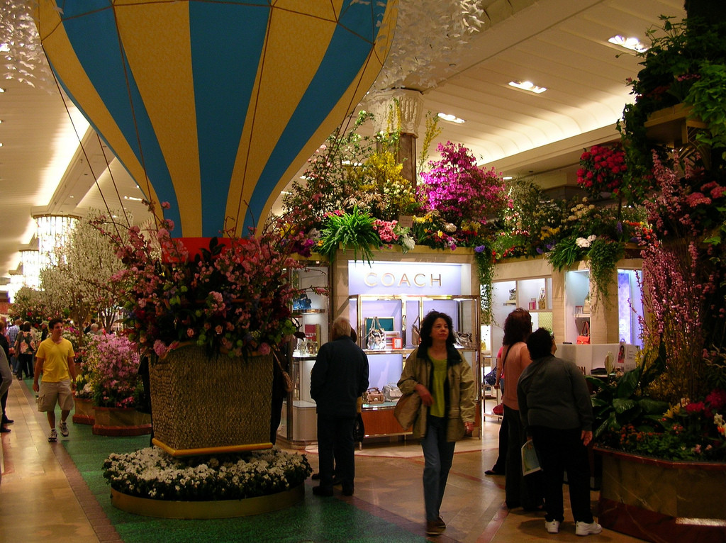 Photo of main floor of Macy's department store, decorated with flowers and a large hot-air balloon and several shoppers.
