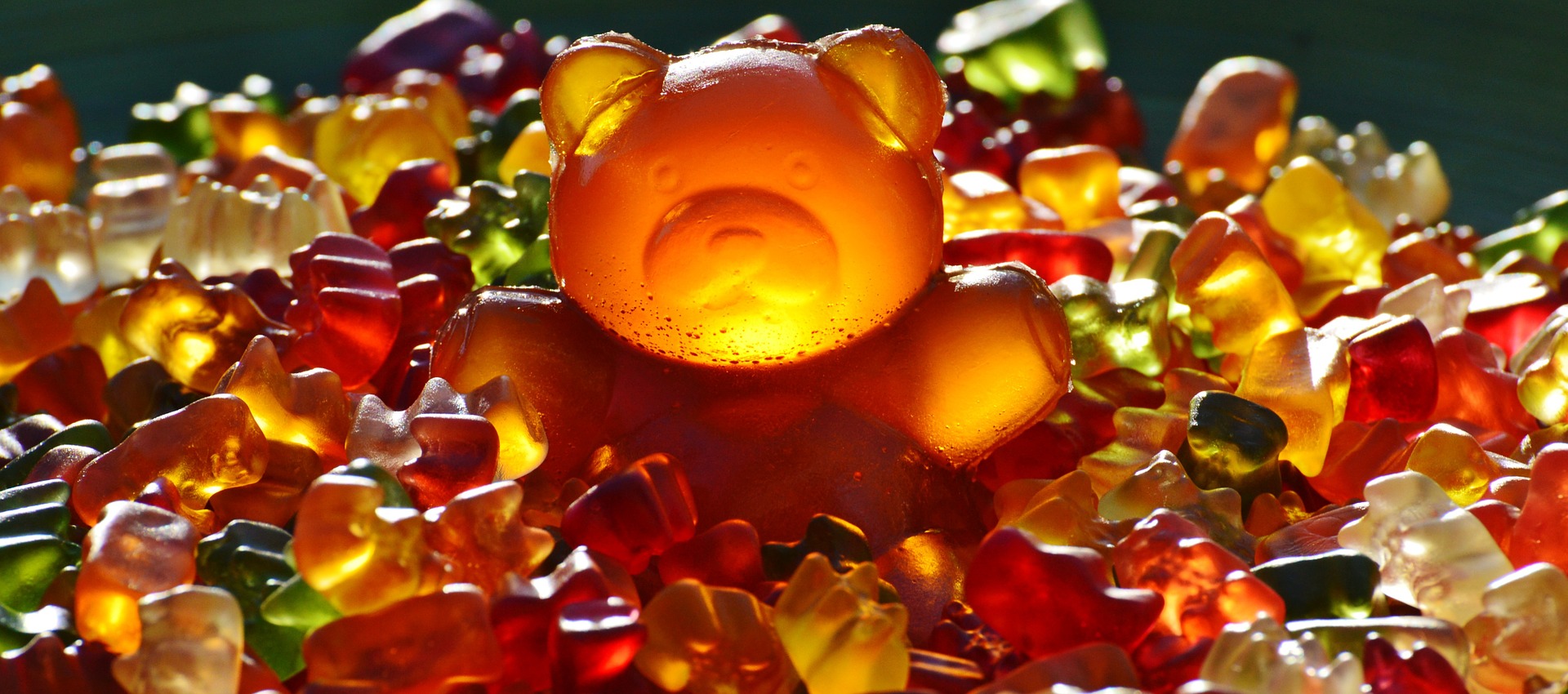 An enormous gummy bear surrounded by tiny gummy bears.