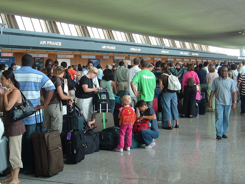 People waiting in long lines in a crowded airport.