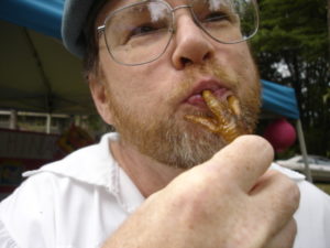 Photo of a man with a fried chicken foot in his mouth.